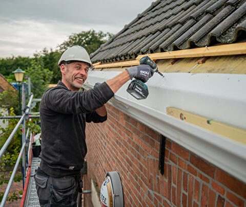 Tradesman fitting a new gutter